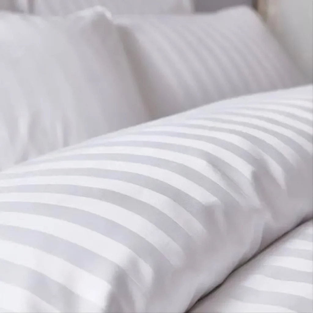 Close-up of a striped quilt cover laid perfectly flat, demonstrating how Kanga Duvet Clips maintain straight, uniform lines without bunching.